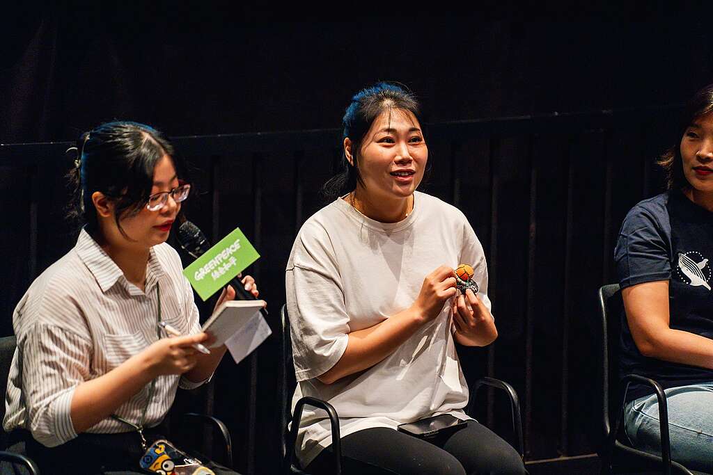 韓國濟州島海女 Youjung 在映後談展示佩戴的「浮標」胸章——除了用來放置漁獲,以及讓海女倚靠休息,顯眼的橙黃色亦能警示附近船隻避免駛近工作中的海女,一物三用。 © Greenpeace / Tree Chow