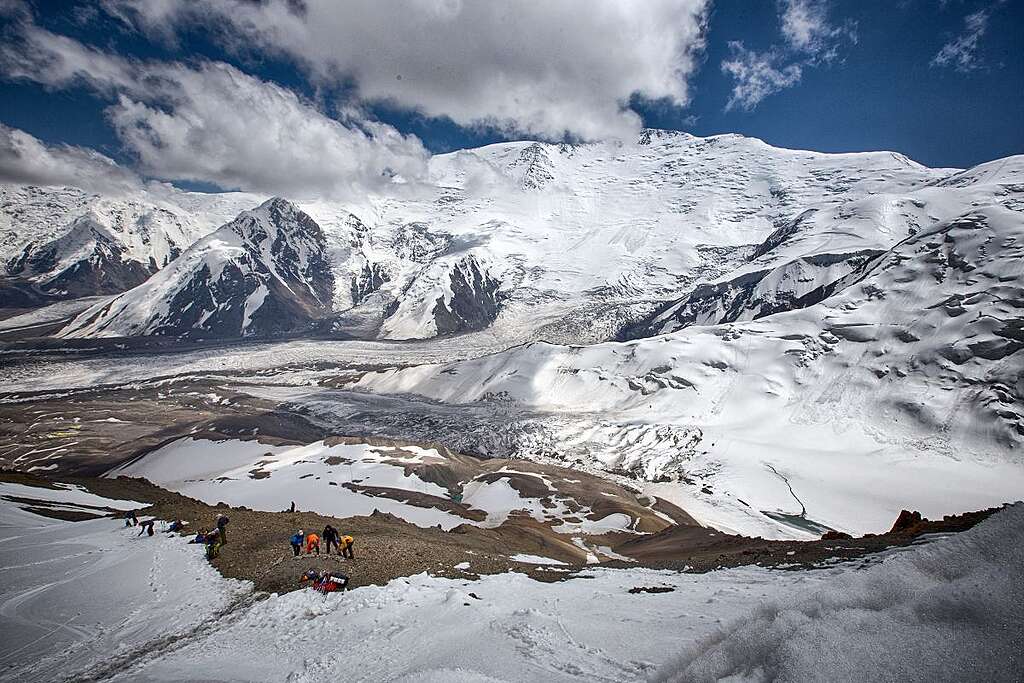 帕米爾山脈列寧峰(7,134 米)的廣闊雪坡與冰川盆地,前景可見登山隊活動區域。我以獨攀方式穿越冰川與冰縫帶,遠處為延伸的冰雪山體。© Wilson Cheung