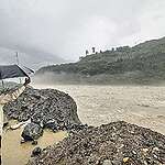 TOPSHOT - In this photograph taken on July 9, 2023, a man holds an umbrella while standing on the banks of swollen river Satluj after heavy monsoon rains in Rampur, in India's Himachal Pradesh state. Hill states were the worst affected, leaving six dead in Himachal Pradesh alone where landslides blocked about 700 roads, Omkar Sharma, a disaster management official told AFP. (Photo by AFP) (Photo by -/AFP via Getty Images)