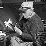 Poet Lawrence Ferlinghetti sits reading a paperback book at Caffe Trieste in 2012. Photo by Cmichel67 / Wikimedia Commons (CC BY-SA 4.0)
