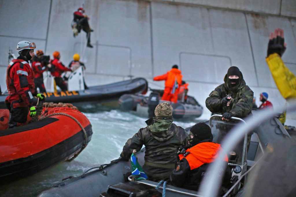 A Russian coast guard officer is seen pointing a gun at a Greenpeace International activist as five activists attempt to climb the 'Prirazlomnaya,' an oil platform operated by Russian state-owned energy giant Gazprom platform in Russia’s Pechora Sea.