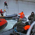 A Russian coast guard officer is seen pointing a gun at a Greenpeace International activist as five activists attempt to climb the 'Prirazlomnaya,' an oil platform operated by Russian state-owned energy giant Gazprom platform in Russia’s Pechora Sea. 