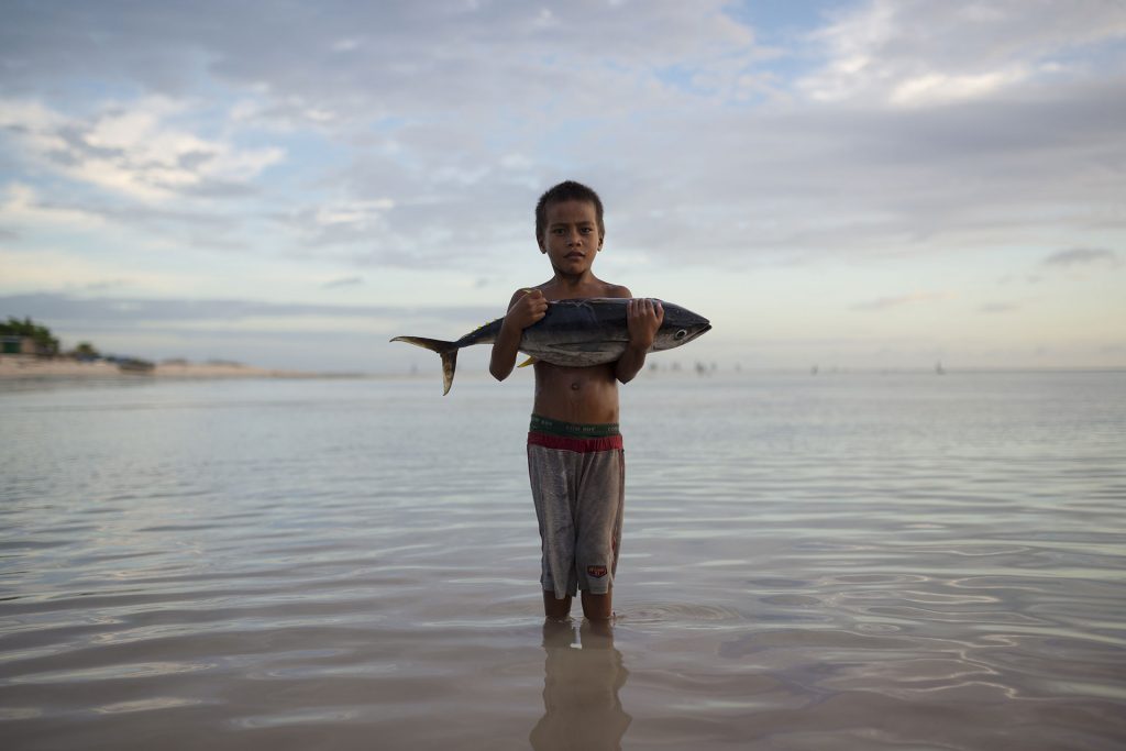 Boy with Tuna Fish Stands in Sea © Christian Åslund / Greenpeace