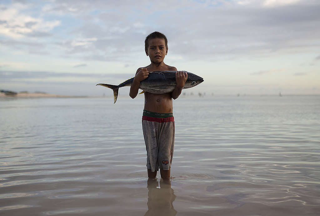 Boy with Tuna Fish Stands in Sea © Christian Åslund / Greenpeace