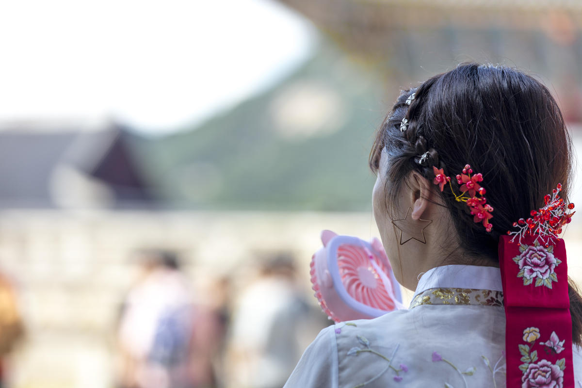 A tourist in Gyongbok Palace cools down from the heat using a toy fan. © Soojung Do / Greenpeace