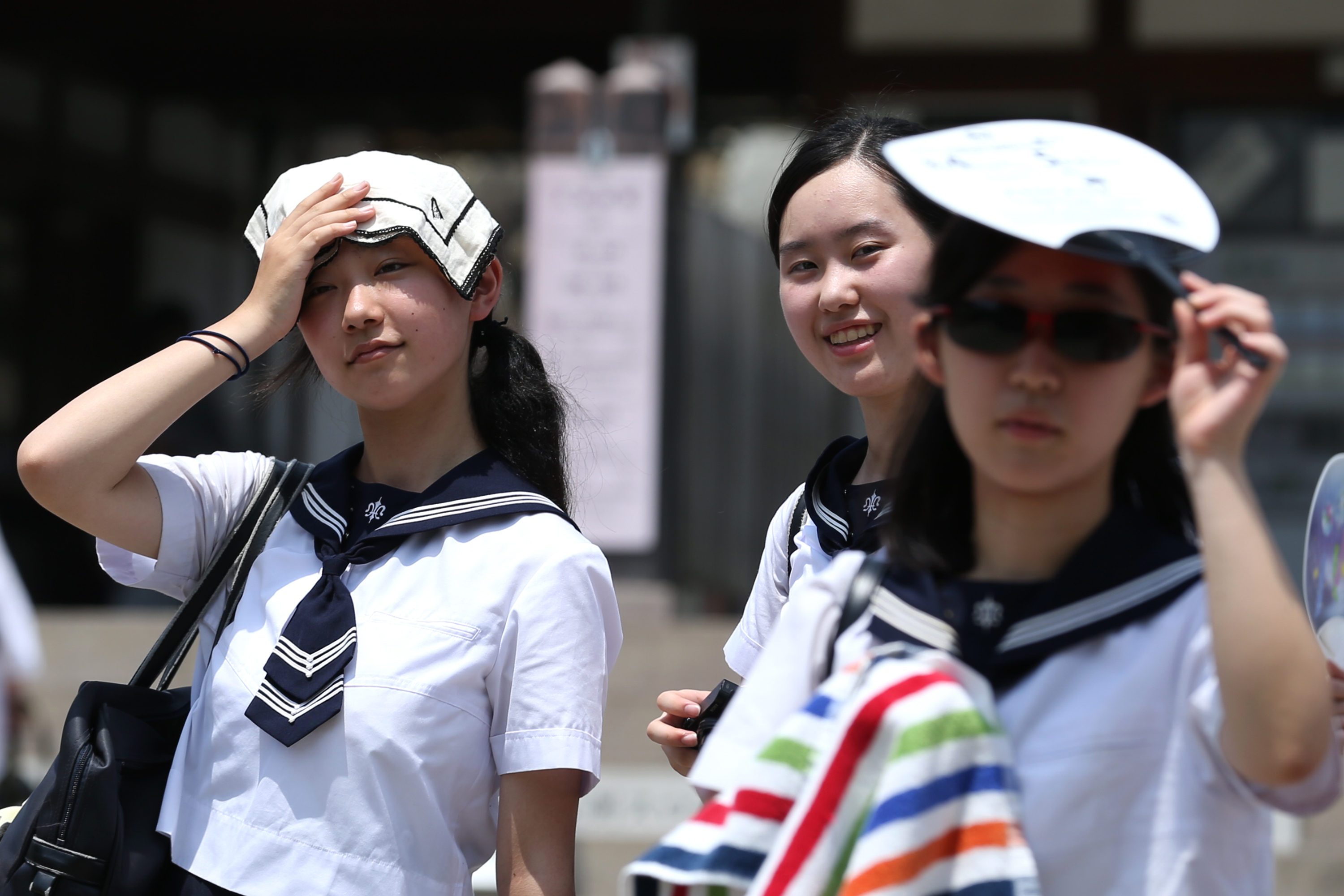 Japanese high school students use a handkerchief to cover their heads from sunlight as city temperature reach 36 degree celsius in Himeji, Japan. A natural disaster has been declared as thousands of people have been taken to hospital with heat stroke as the death toll continues to rise in Japan following the record-breaking heat wave. Photo: Buddhika Weerasinghe/Getty Images