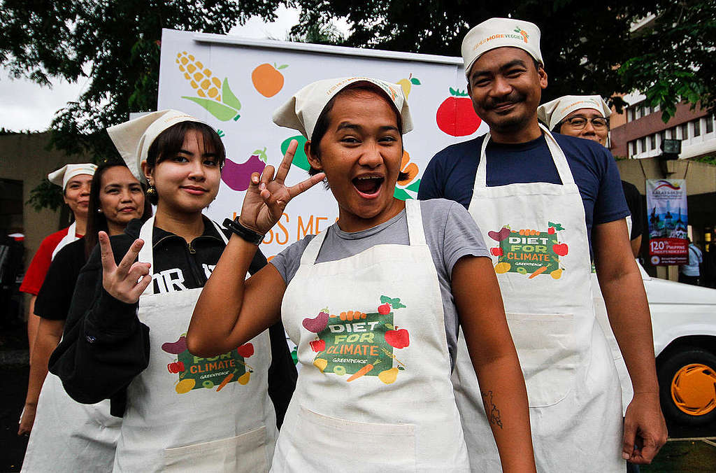 Greenpeace volunteers in the Philippines pose wearing aprons and chef hats as they prepare to serve plant-based snacks at Quezon City Hall to build public support for healthy, sustainable meal options in schools.