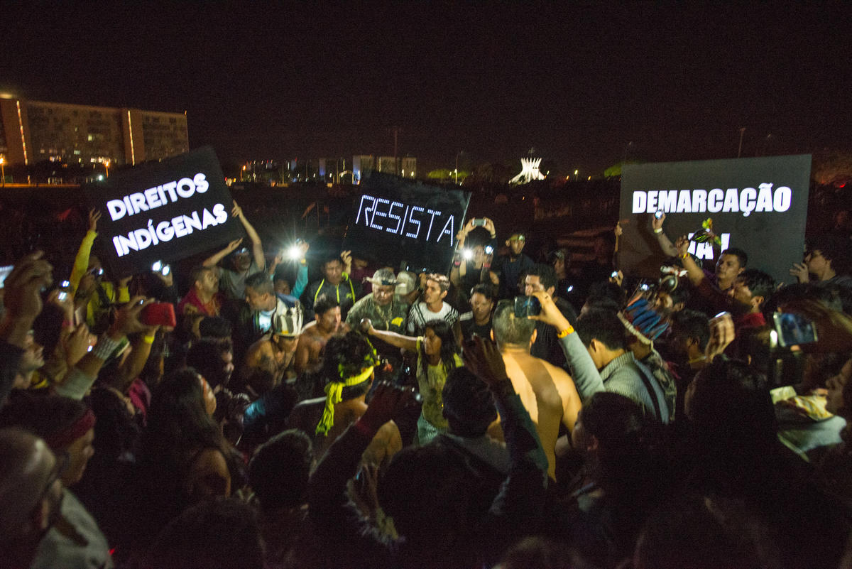 Indigenous People hold “Resist” signs and signs demanding the official recognition of the lands. © Christian Braga / MNI