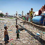 Children playing on a beach covered in plastic waste in Manila.