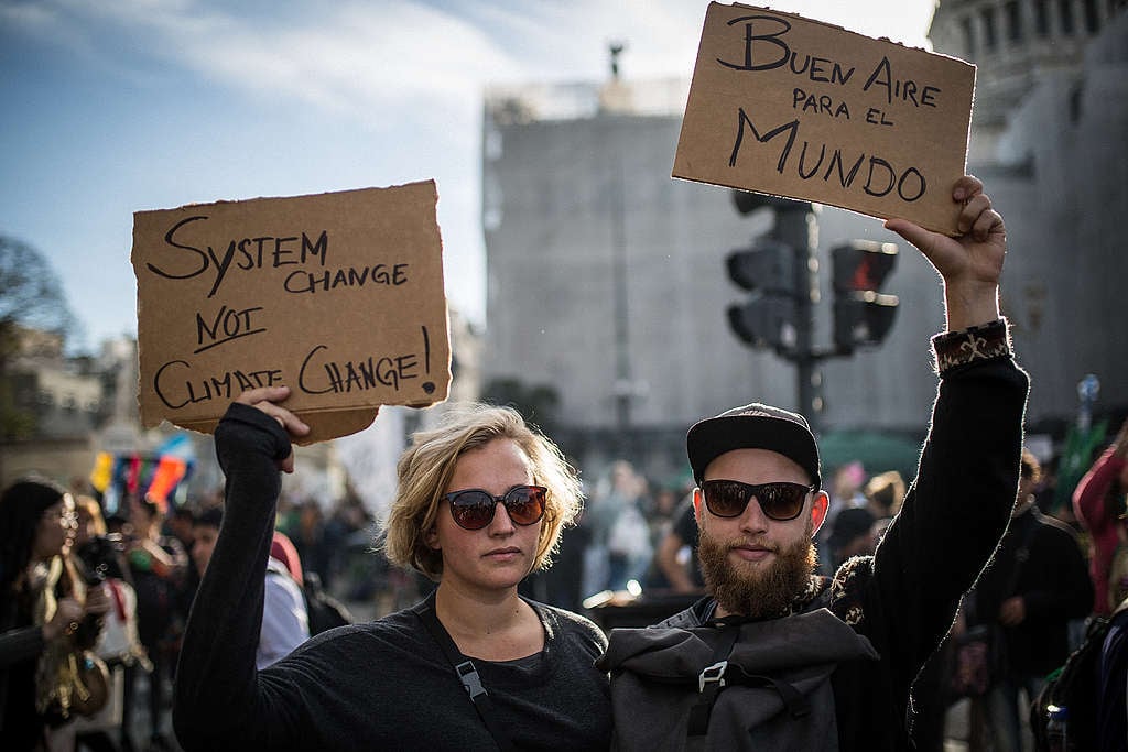 ©Nicolás Villalobos/Greenpeace Activists holding up signs demanding clean air and system change at a climate march in Buenos Aires, Argentina