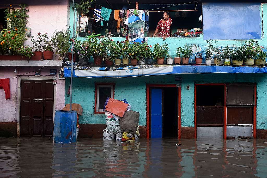 A resident stands from her balcony as the Bagmati River overflowed following monsoon rains in Kathmandu on July 20, 2020.  © PRAKASH MATHEMA/AFP via Getty Images