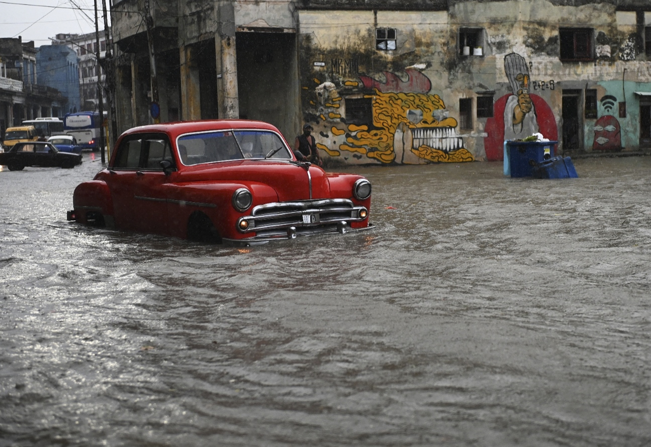 An old American car drives through a flooded street in Havana, Cuba. © Yamil Lage/AFP via Getty Images
