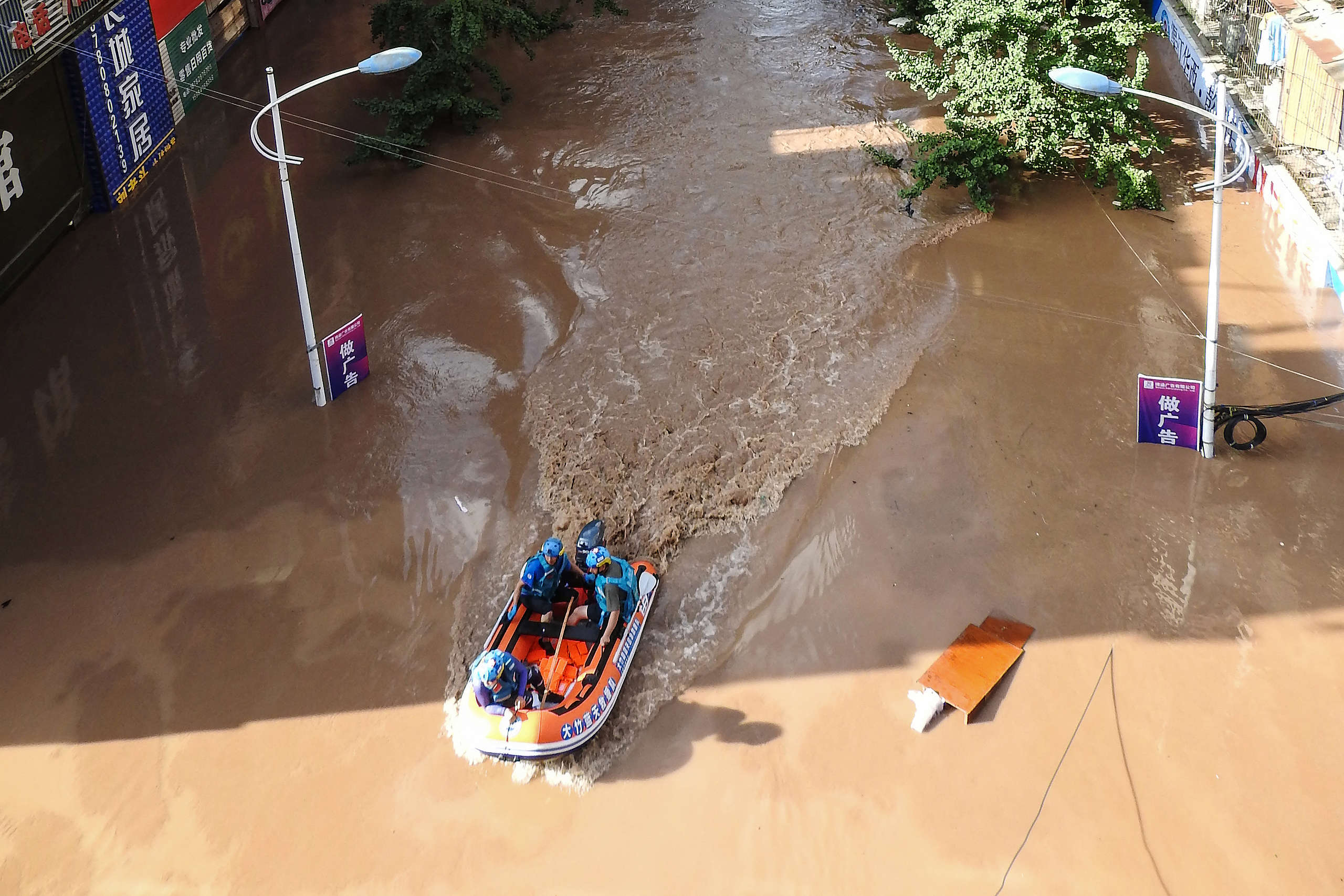 Rescuers looking for stranded residents along a flooded street following heavy rains in Dazhou, China. © STR/AFP via Getty Images