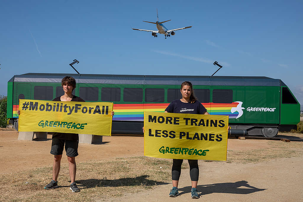 Activists from Greenpeace Spain hold a banner that reads: "more trains and fewer planes". © Greenpeace / Pablo Blázquez Activists from Greenpeace Spain hold a banner that reads: "more trains and fewer planes". © Greenpeace / Pablo Blázquez