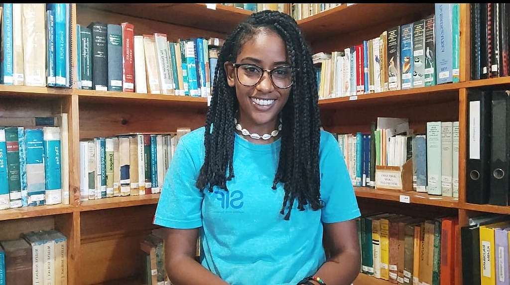Emma Mederic, 23, in an aqua SIF (Seychelles Island Foundation) t-shirt in front of bookcases. © Emma Mederic Emma Mederic, 23, in an aqua SIF (Seychelles Island Foundation) t-shirt in front of bookcases. © Emma Mederic