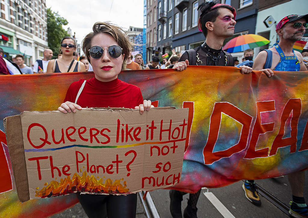 A person holds a sign that reads 'Queers like it Hot. The Planet? Not so much.' © Marten van Dijl / Greenpeace Picture showing a Queers4Climate activists standing against climate breakdown and holding a sign reading "Queers like it hot. The planet? Not so much."