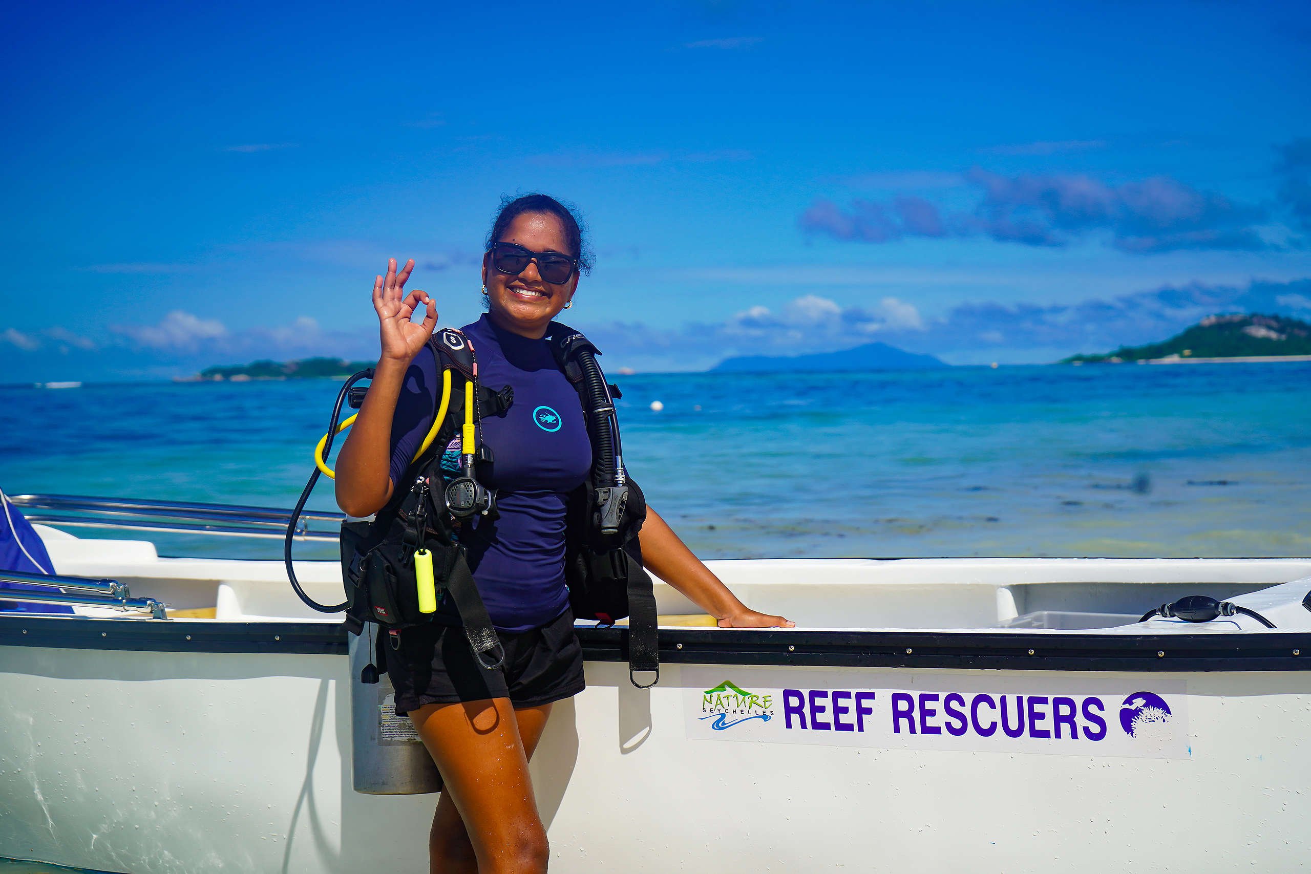 25-year old Athina Antoine, sunglasses and dark blue swim top and shorts, has been a part of the Nature Seychelles’ Reef Rescuers (white boat) team since 2017