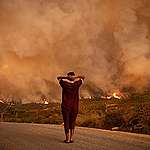 A woman looks at wildfires tearing through a forest in the region of Chefchaouen in northern Morocco