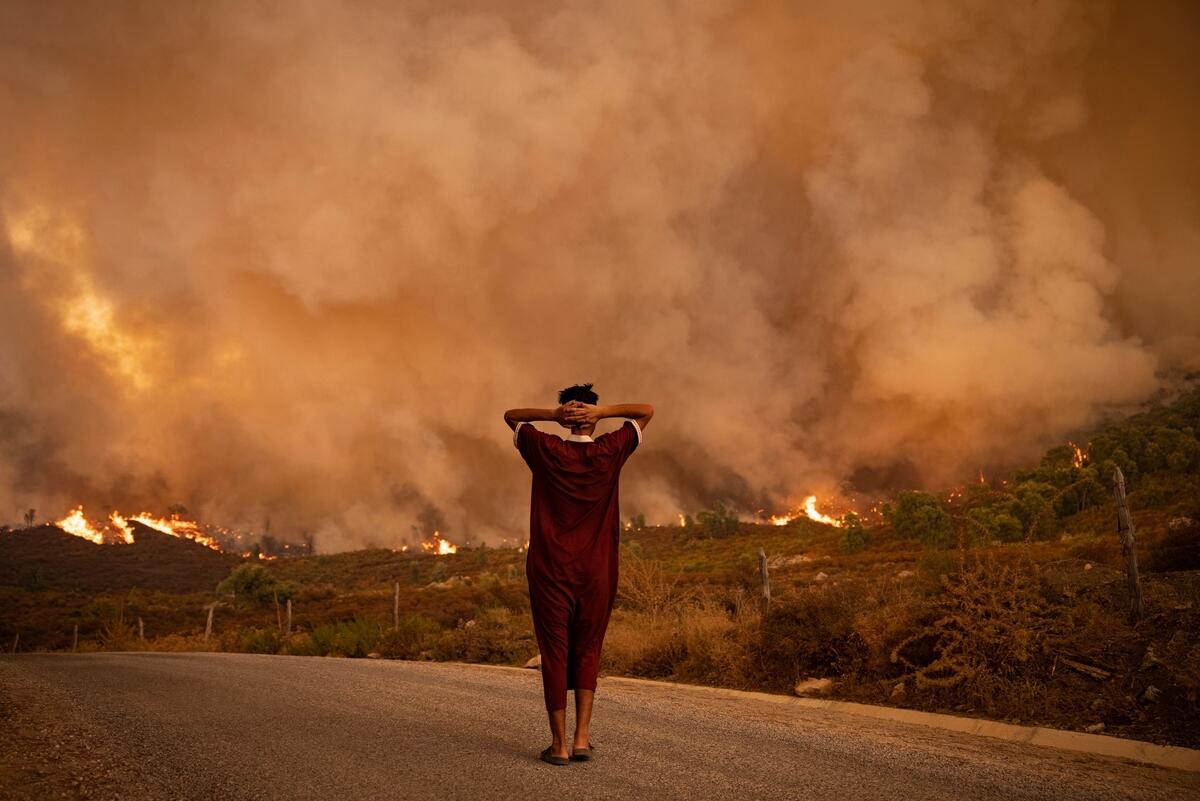 A woman looks at wildfires tearing through a forest in the region of Chefchaouen in northern Morocco