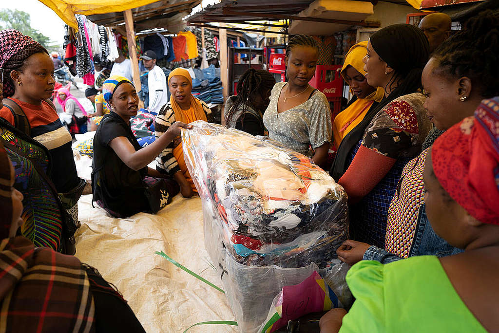 Fast Fashion Research in Tanzania. Mitumba Market Mbauda in Arusha, Tanzania. When opening a bale of second-hand clothes the tension is high: is the content good enough to be sold again or is a lot of it just textile waste? © Kevin McElvaney / Greenpeace
