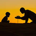 Silhouette of San on top of dunes at sunset. Stampriet District, Namibia