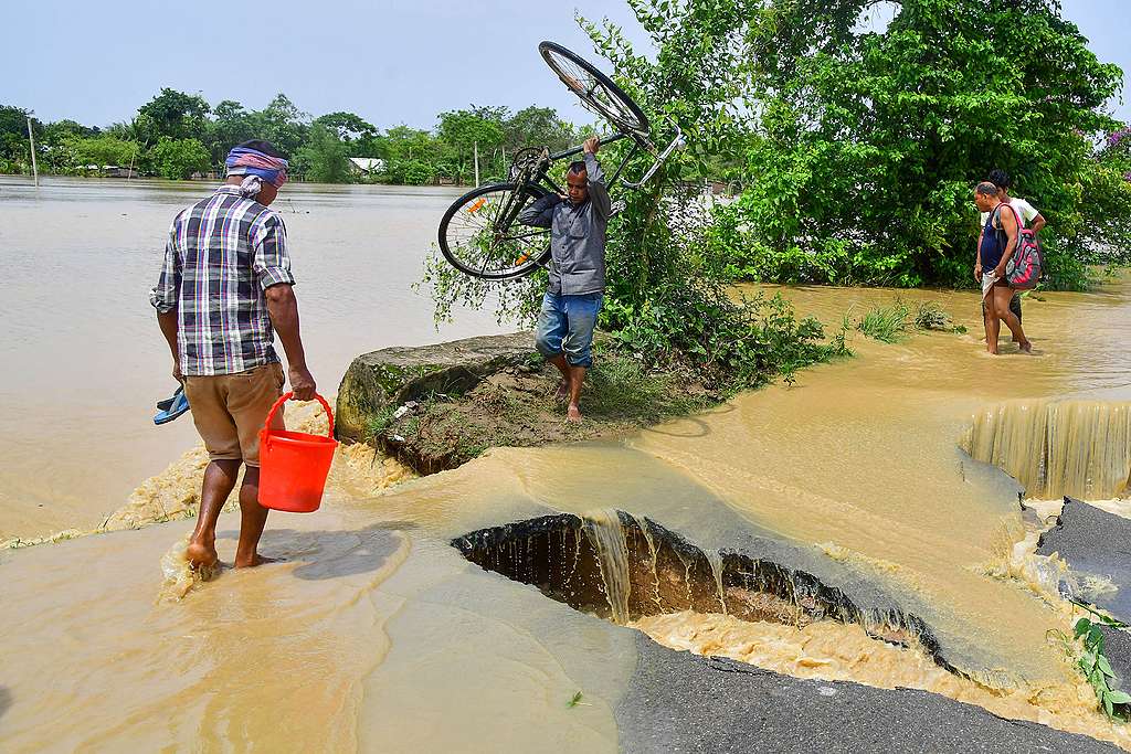 A man carrying his bicycle crosses a damaged road due to flooding after heavy rains in Nagaon, Assam, on May 19, 2022. - At least 10 people, including a four-year-old child have died in floods and landslides this week after unusually heavy rains pummelled several parts of India, as forecasters warned on May 18 of more deluges. © BIJU BORO/AFP via Getty Images