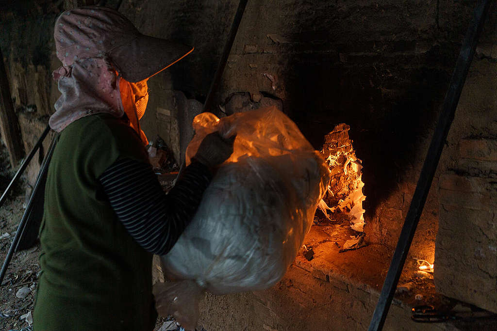 A woman loads garment offcuts into a brick kiln located in Kandal Province, Cambodia.
