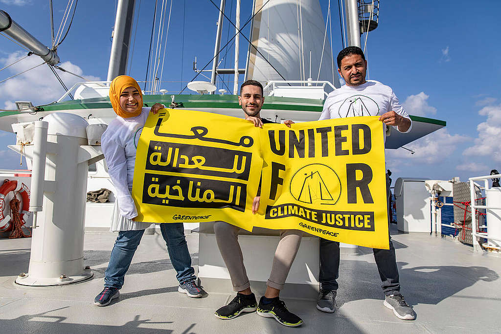 Youth climate champions holding banners for the United for Climate Justice campaign, on-board the Rainbow Warrior, in the Mediterranean Sea.