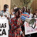 Campaigners in Africa hold up banners and use a megaphone to call for an end to fossil-fuel-induced energy apartheid.