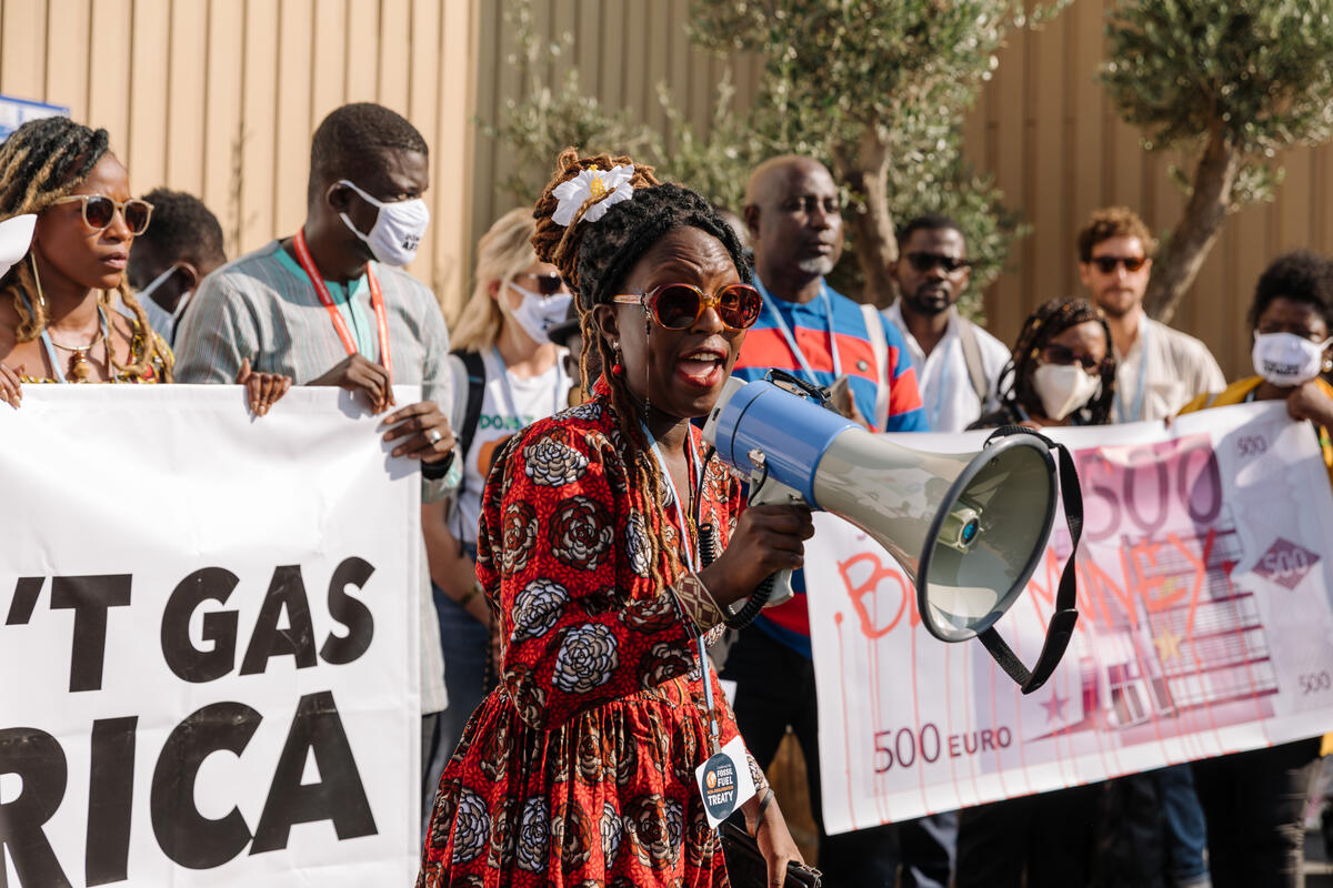 Campaigners in Africa hold up banners and use a megaphone to call for an end to fossil-fuel-induced energy apartheid.