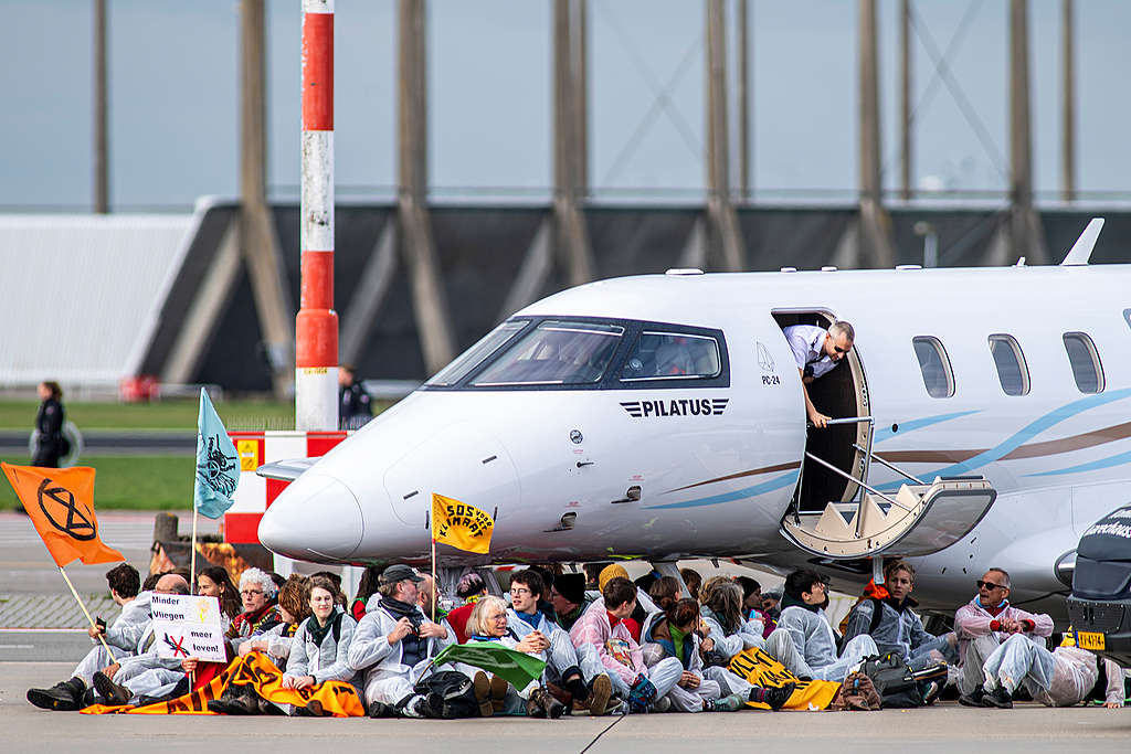 A large group of activists from Extinction Rebellion and Greenpeace Netherlands hold a peaceful protest at Amsterdam Schiphol Airport, the second biggest in the EU, stopping private jets from landing and taking off and sitting and cycling around the area where private jets are parked. The protesters are people concerned about the climate crisis and local residents whose lives are affected by the noise and air pollution from Schiphol Airport. The airport should be reducing its flight movements, but is instead even building a brand new terminal. We need a smaller airport, we want fewer flights, more trains and a ban on unnecessary short-haul flights. © Marten  van Dijl / Greenpeace