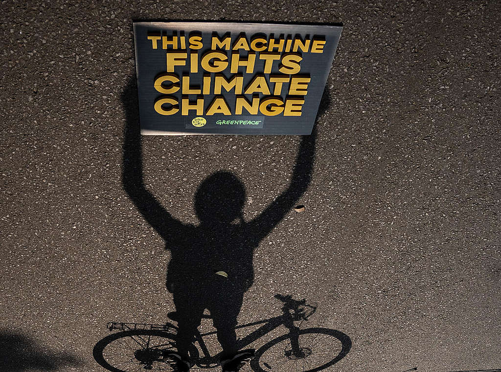 A shadow of Greenpeace Indonesia activist holds the banner reading "This Machine Fights Climate Change" during a commemoration of World Bicycle Day and World Environment Day in Jakarta. Thousands of cyclists from the Bike To Work communities joined the rallies. © Jurnasyanto Sukarno / Greenpeace