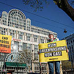 Climbers from Greenpeace Central and Eastern Europe hang a six-by-eight-metre banner reading "End Fossil Crimes" on the European Gas Conference venue in Vienna. (the Vienna Marriott Hotel) in protest against the fossil fuel industry’s plans to “future-proof gas” in the face of climate disaster. Greenpeace is calling for fossil fuel companies to stop their climate-wrecking activities and be held accountable for their crimes. Woman holds banner in the foreground to protest industry greenwashing.