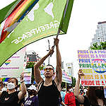 Greenpeace activists hold placards with messages that support climate justice and gender justice in Bangkok Pride parade.