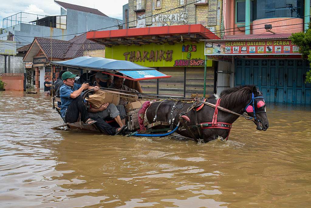 La gente guida una carrozza trainata da cavalli attraverso una strada allagata dall'inondazione del fiume Citarum nel villaggio di Sucaberus a Bandung, in Indonesia, il 6 maggio 2023. Foto di Timur Matahari/AFP tramite Getty Images