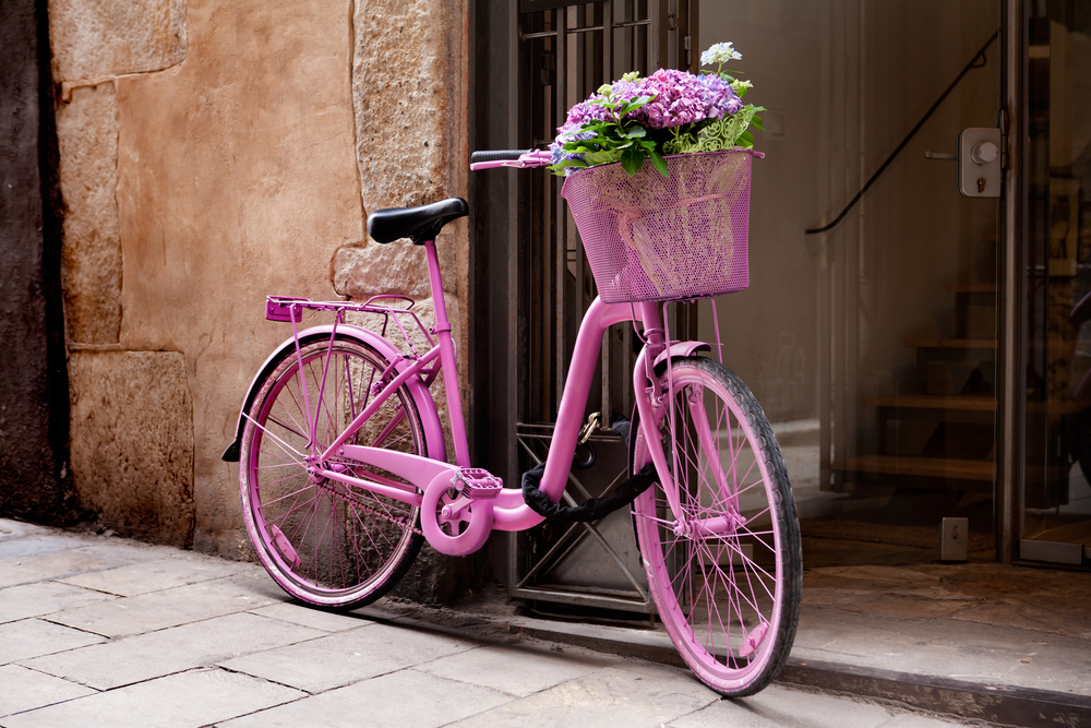 Pink bicycle with flowers in the front basket