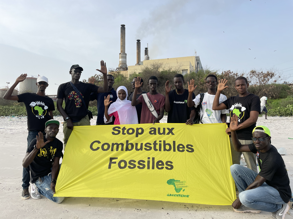 Group of people hold up hand behind a yellow banner reading "End Fossil Fuels" in French during global mobilisation to End Fossil Fuels Group of people hold up hand behind a yellow banner reading "End Fossil Fuels" in French during global mobilisation to End Fossil Fuels