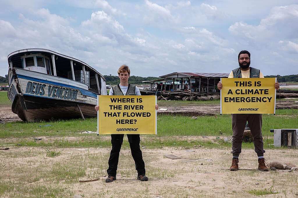 Greenpeace activists hold banners in a dry lake © Marizilda Cruppe / Greenpeace