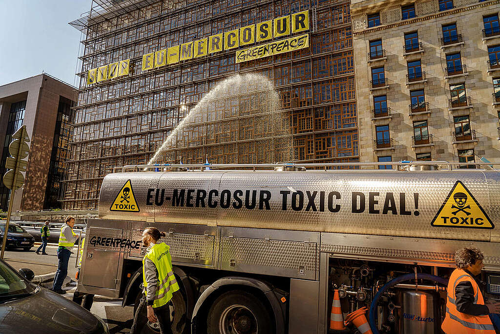 Activists from Greenpeace Belgium scale the EU Council headquarters in Brussels and hung banners on the facade of the building reading “Stop EU-Mercosur” while an agricultural truck sprayed clouds of water to simulate pesticides. © Eric De Mildt / Greenpeace