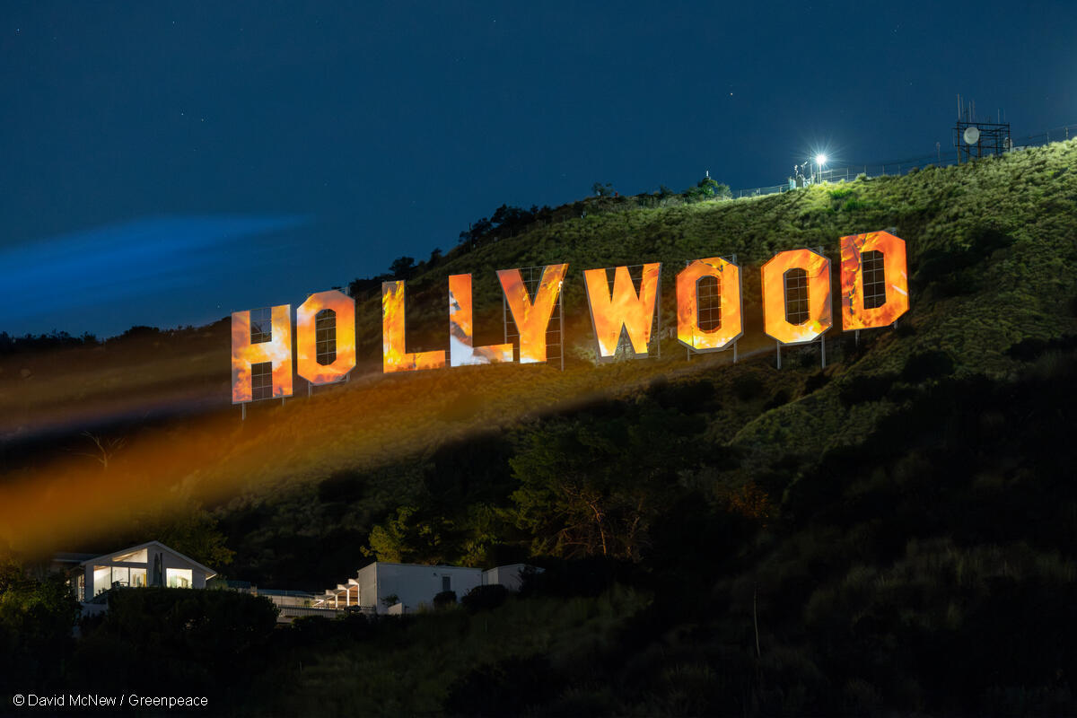 Image of iconic Hollywood sign in Los Angeles, California. Greenpeace USA projection depicts flames on the sign.