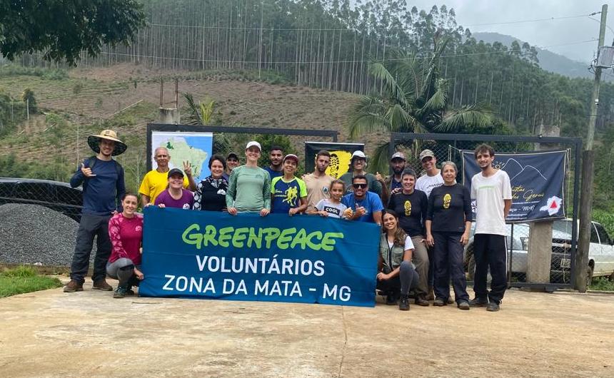 A group of volunteers holding up a banner that says Greenpeace Voluntarios Zona da Mata - MG.