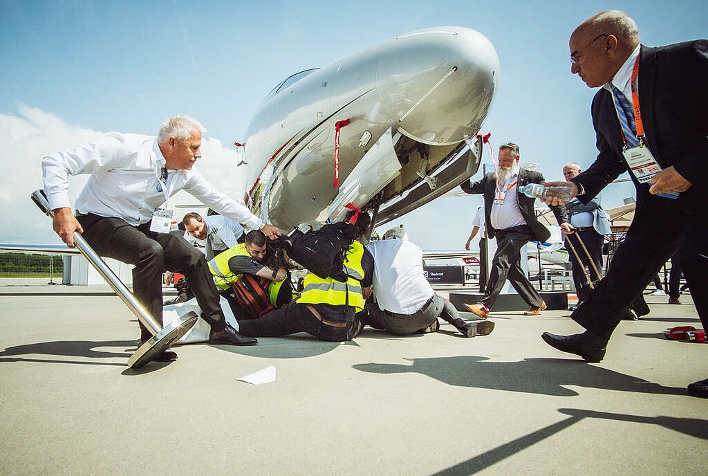 A hundred climate activists supporting Greenpeace, Stay Grounded, Extinction Rebellion, Scientist Rebellion and other climate movement groups from 17 countries have disrupted Europe's biggest private jets sales fair, the annual European Business Aviation Convention & Exhibition (EBACE) in Geneva, demanding a ban on private jets.  Activists were peacefully occupying private jets that are exhibited at the business event by Geneva airport, having chained themselves to aircraft gangways and the exhibition entrance in order to keep prospective buyers from entering. The protestors stuck giant tobacco-style health warning labels on the airplanes marking them as toxic objects and warning that 'private jets burn our future', 'kill our planet', and 'fuel inequality'. Public service announcements from loudspeakers carried by the activists exposed the dramatic consequences of private jets for our planet and revealed the hypocrisy of promoting private jets amidst rising social inequality. © Thomas Wolf / Stay Grounded