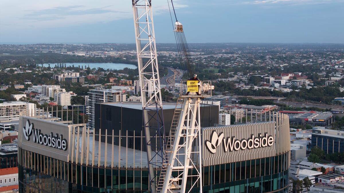 Greenpeace activists drop a 25m 'Stop Woodside' banner from a crane outside Woodside's headquarters in Perth, WA