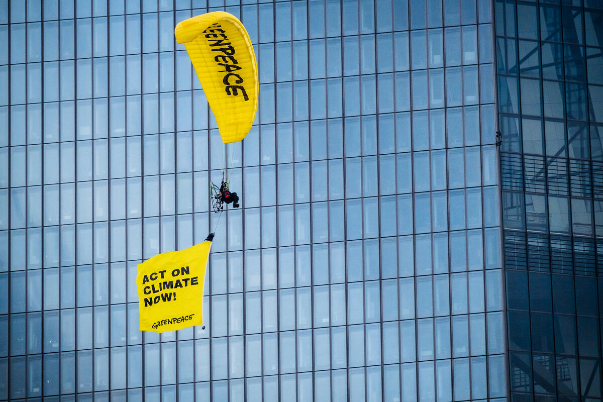 Greenpeace activists demand "Act on climate now" at the headquarters of the European Central Bank (ECB) in Frankfurt. An activist on a paraglider protests with a flying banner. © Bernd Hartung / Greenpeace