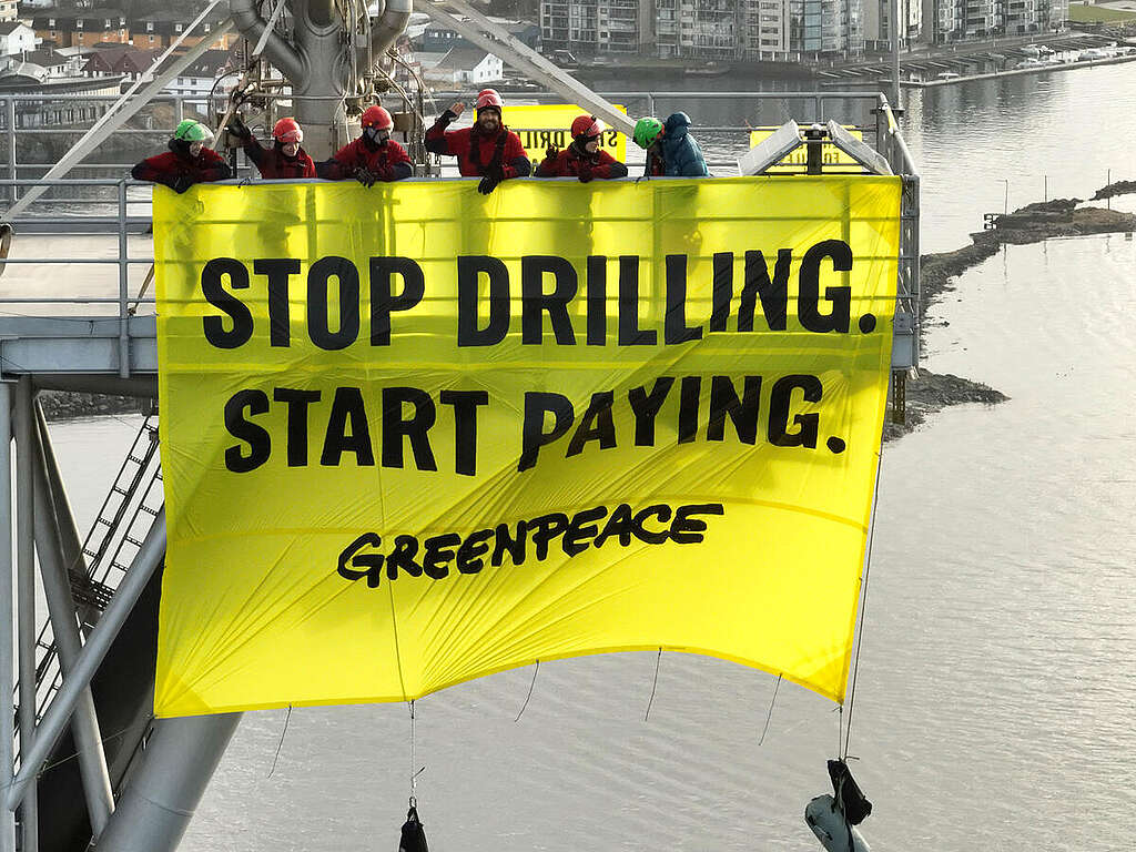 Activists hang a huge banner reading Stop Drilling Start Paying from a Shell oil platform Activists hang a huge banner reading Stop Drilling Start Paying from a Shell oil platform