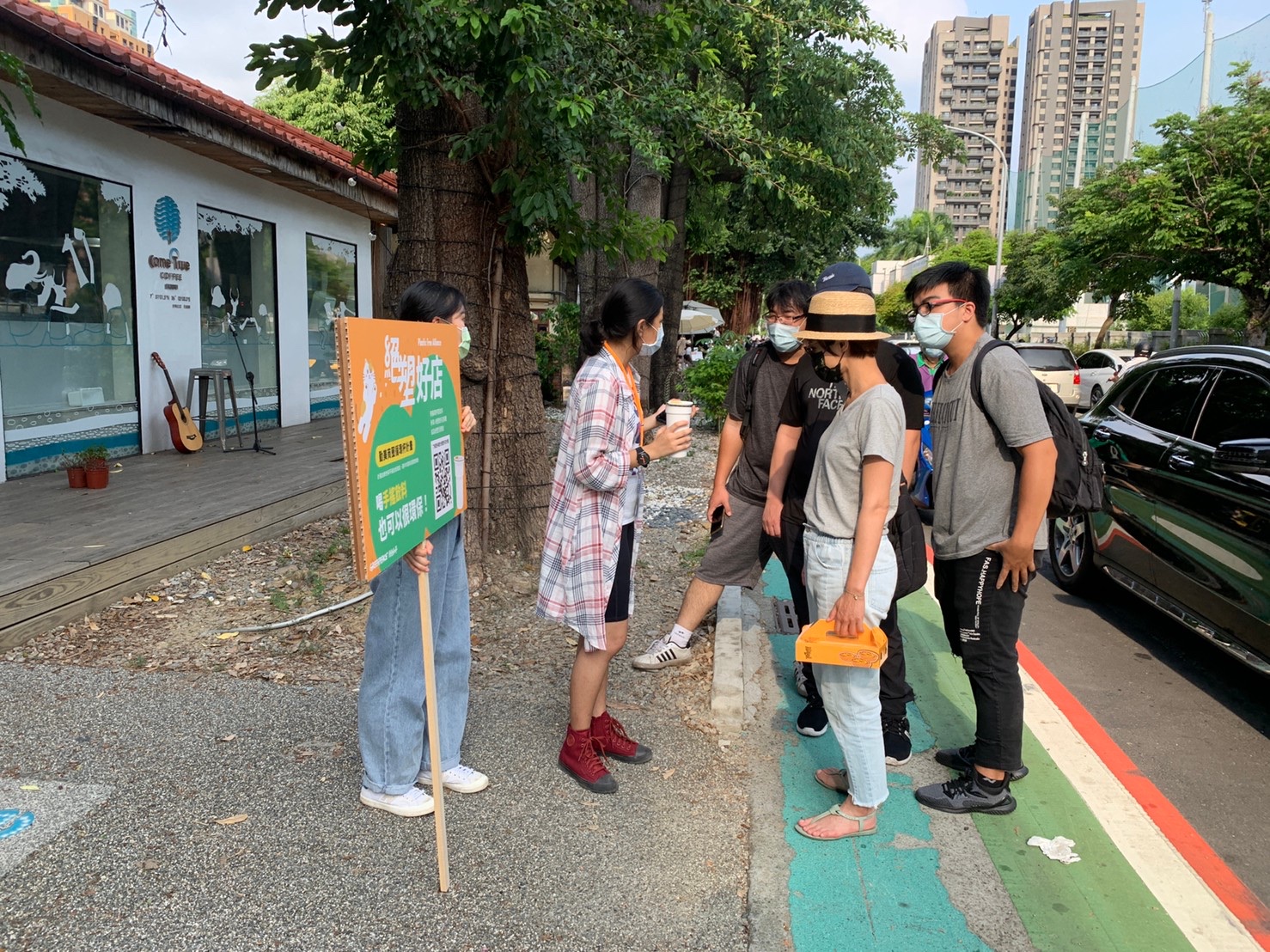 Two greenpeace volunteers explaining the importance of reusable cups to four regular citizens