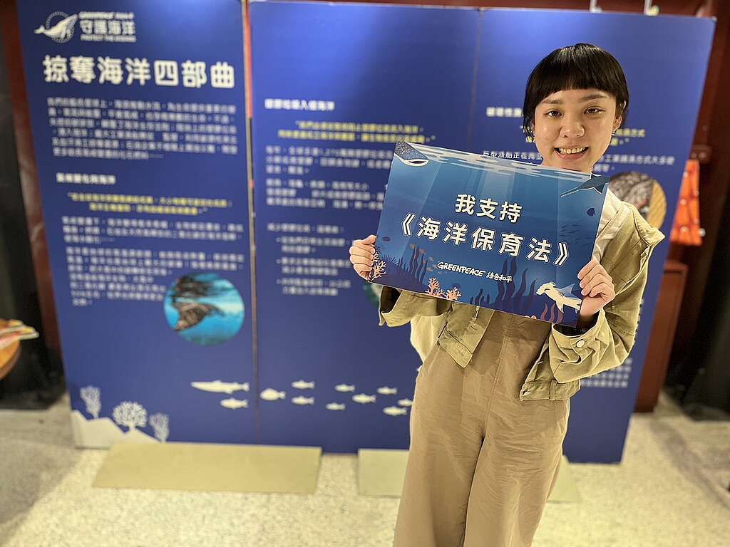 A woman is holding a Greenpeace banner about saving the ocean