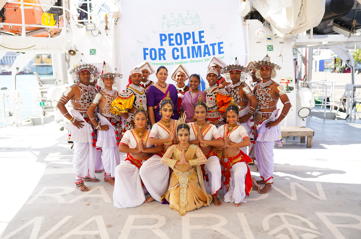 people dressed in traditional Sri Lankan clothes stand in front of banner that says "People For Climate"