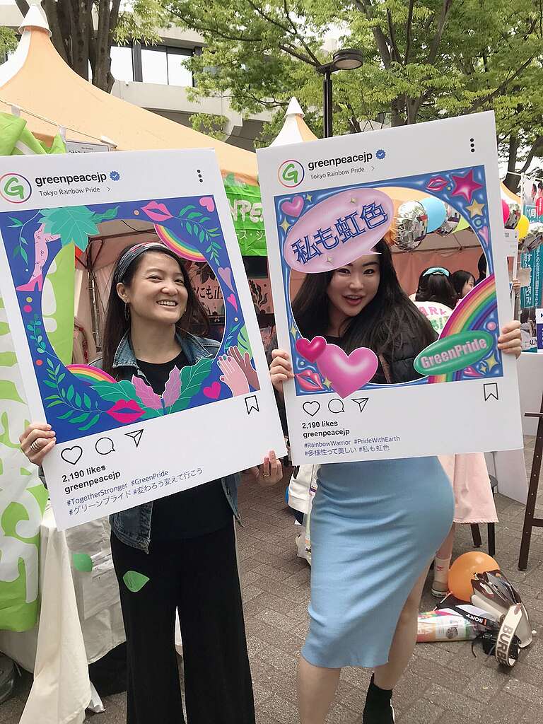 Two women are holding up banners for Greenpeace Japan on the streets