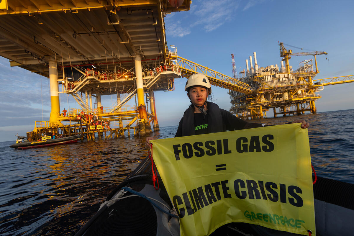 Alliya Moun-Ob, Greenpeace Thailand campaigner carries a hand banner with a message “Fossil Gas =Climate Crisis”at the Arthit fossil gas field to highlight the fossil industry’s greenwashing.